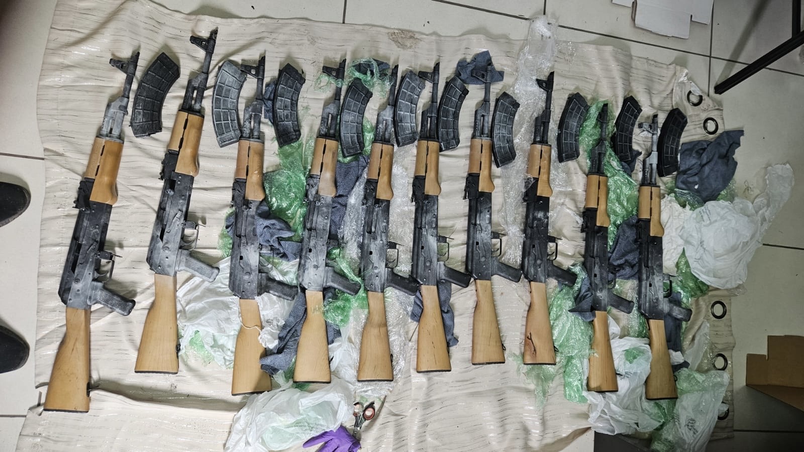 Police find ten AK-47 rifles during operation along No. 11 Village Public Road, Corentyne; one in custody
